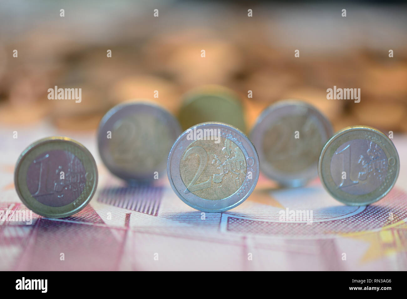Ein- und Zweieuromünzen auf einer Banknote Stockfoto