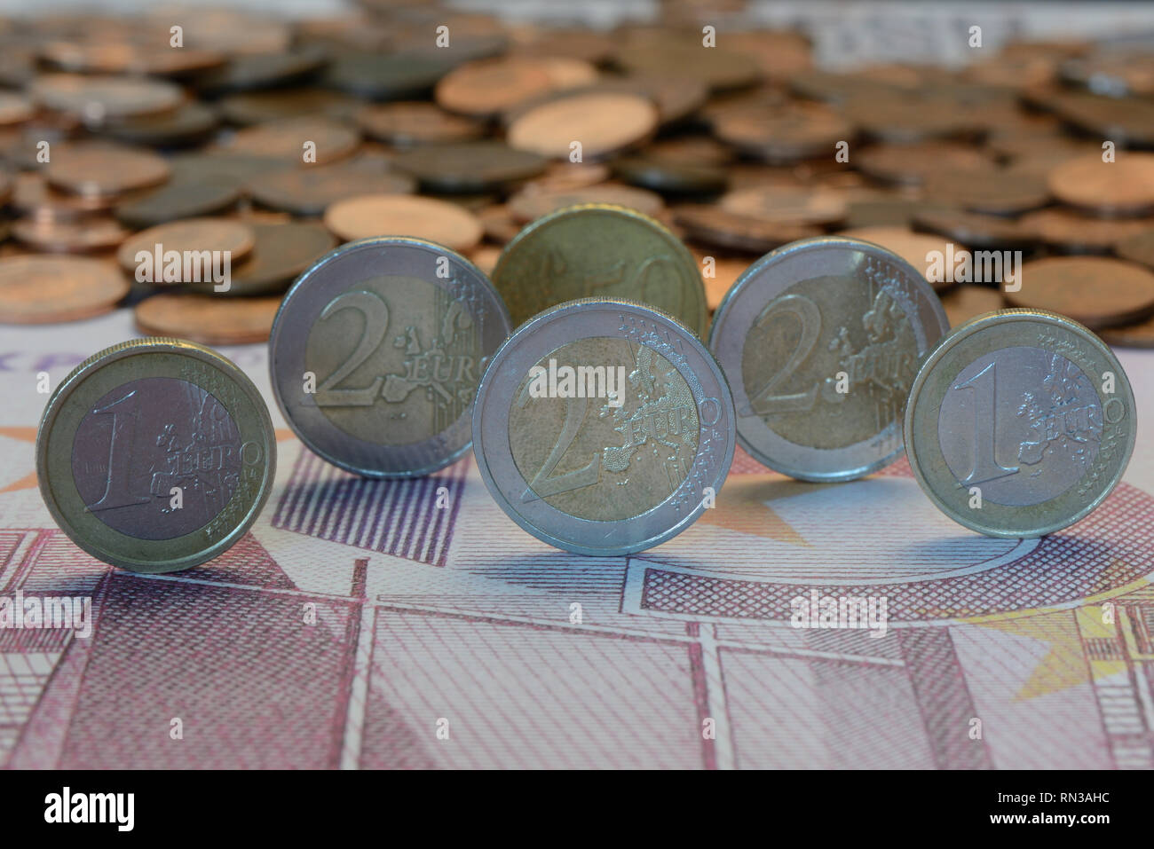 Ein- und Zweieuromünzen auf einer Banknote Stockfoto