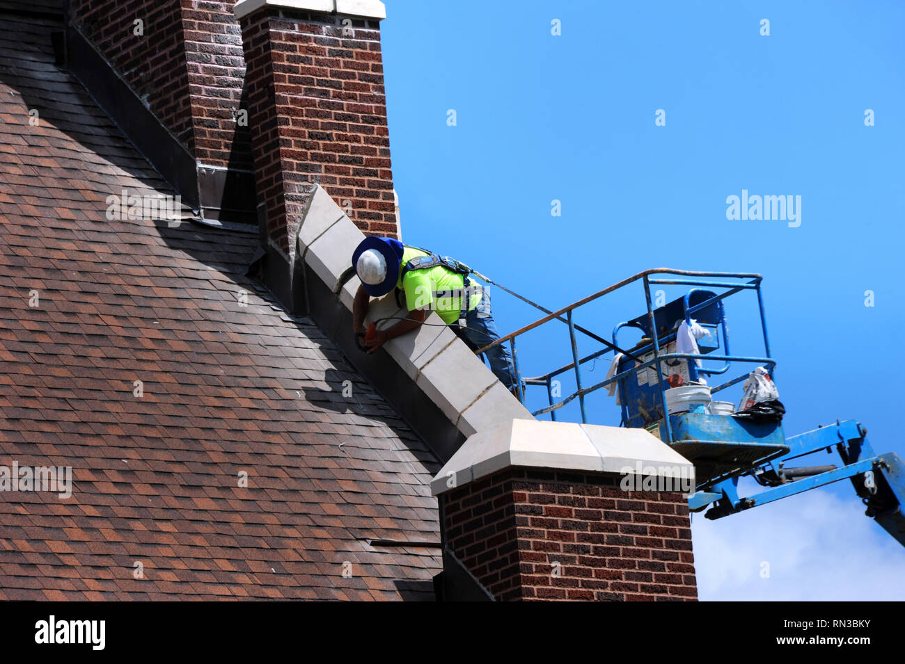 Bauarbeiter verwendet Sander in der Reparatur von Mauerwerk auf einer historischen Kirche in Arkansas. Er steht auf einer Hebebühne und Arbeiten auf die Dachlinie. Stockfoto