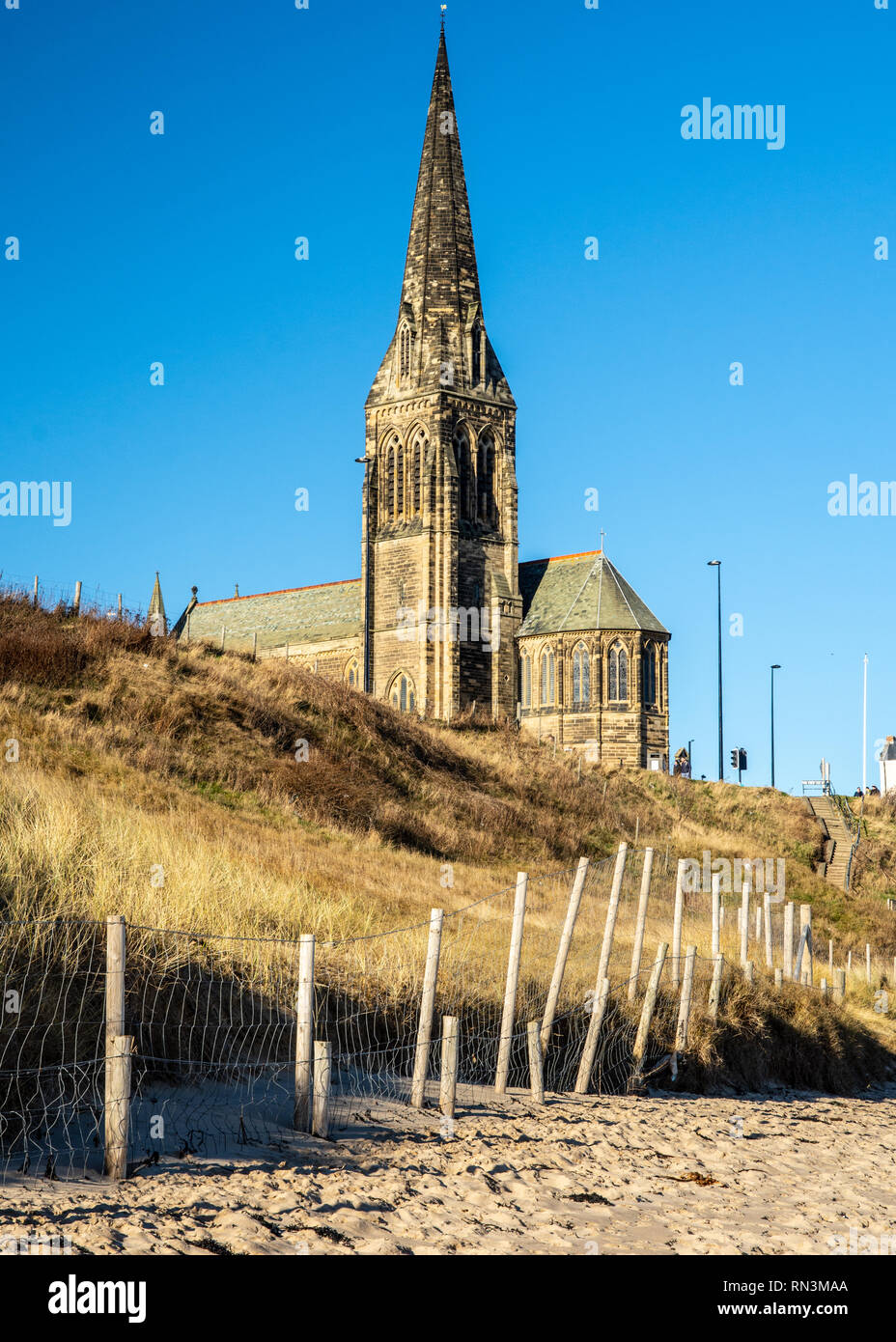 St. George's Kirche Turm erhebt sich über dem Sandstrand von Tynemouth Longsands an Cullercoats im Tyneside. Stockfoto