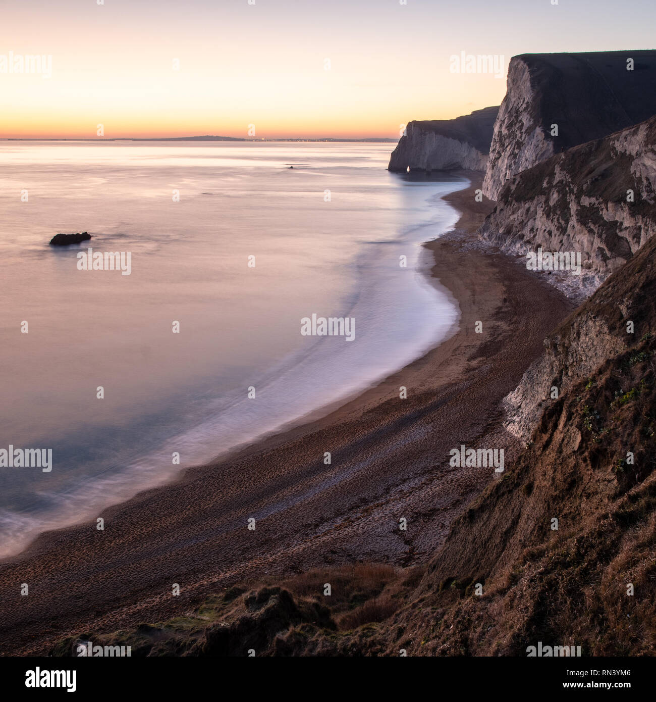 Das Nachleuchten von Sonnenuntergang leuchtet der Himmel hinter dem bat Kopf und Weymouth Bay auf in Dorset Jurassic Coast. Stockfoto