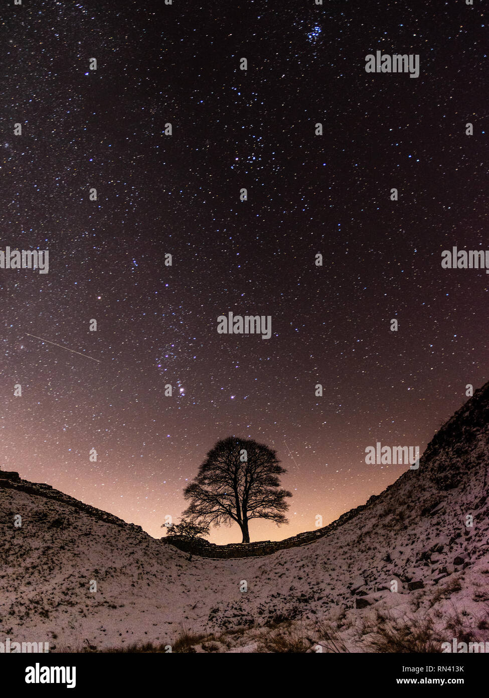 Der Nachthimmel mit Sternen über Sycamore Gap auf dem Hadrianswall in Northumberland gefüllt. Stockfoto