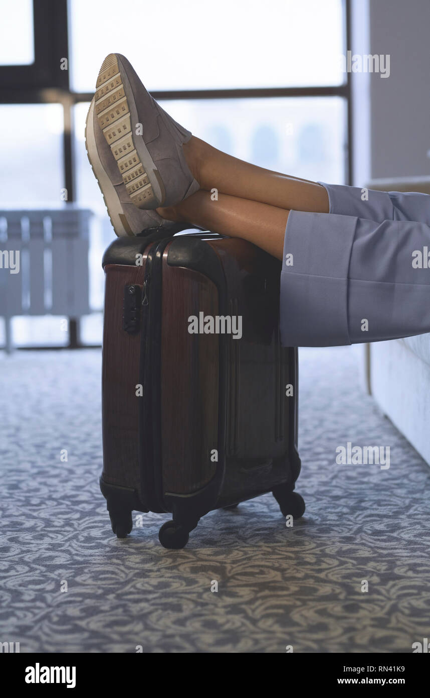 Beine der Geschäftsfrau mit Füßen auf Gepäck Stockfoto