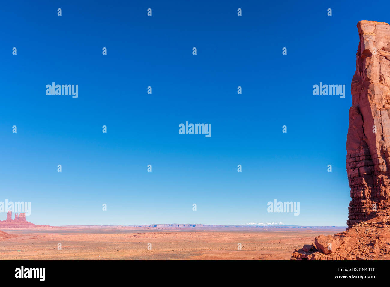 Die malerische Landschaft der trockenen Wüste Plateau von Wind und Wasser mit stark Red Cliff erodiert. Strecke der schneebedeckten Berge in der Ferne unter blauem Himmel. Stockfoto