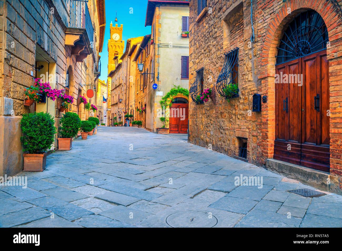 Spektakuläre traditionelle Toskana Blick auf die Straße. Bewundernswert mittelalterliche Häuser aus Stein und gepflasterte Strasse mit blumigen Eingänge, Pienza, Toskana, Italien, Europa Stockfoto