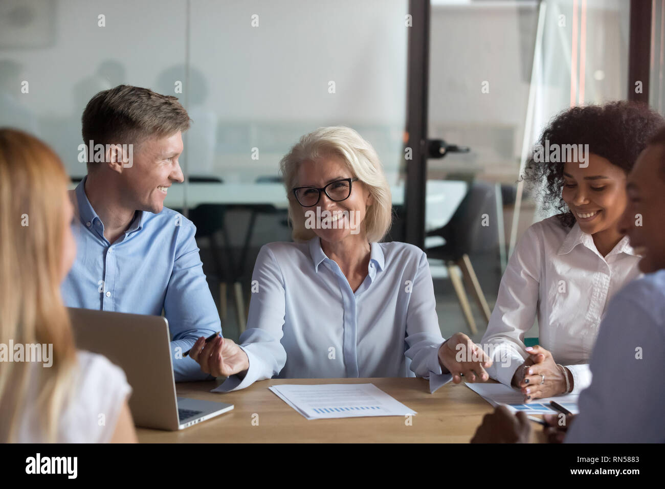 Fünf multinationale Menschen sitzen im Sitzungssaal über Projekt Stockfoto