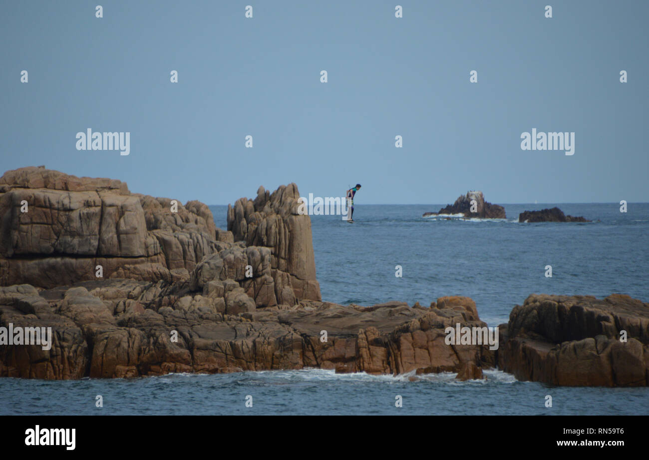 Junge Männer Springen Klippen ins Meer' Coasteering' von der Küste Weg zwischen Cobo Bay & Saline Bay auf Guernsey, Channel Islands.DE gesehen. Stockfoto