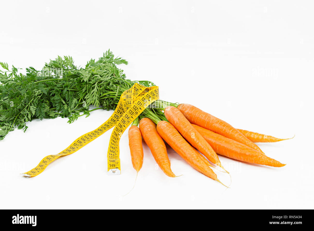 Vegetarische Ernährung, Gewicht zu reduzieren. Ein Haufen frisch gepflückte Karotten in einem Körper Maßband Herrscher, die Bordkante symbolisiert gewickelt Stockfoto