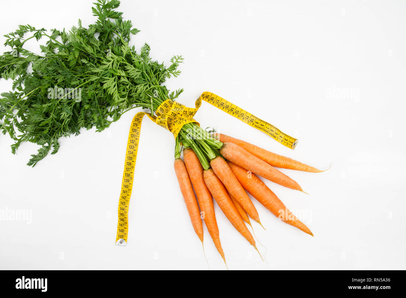 Vegetarische Ernährung, Gewicht zu reduzieren. Ein Haufen frisch gepflückte Karotten in einem Körper Maßband Herrscher, die Bordkante symbolisiert gewickelt Stockfoto