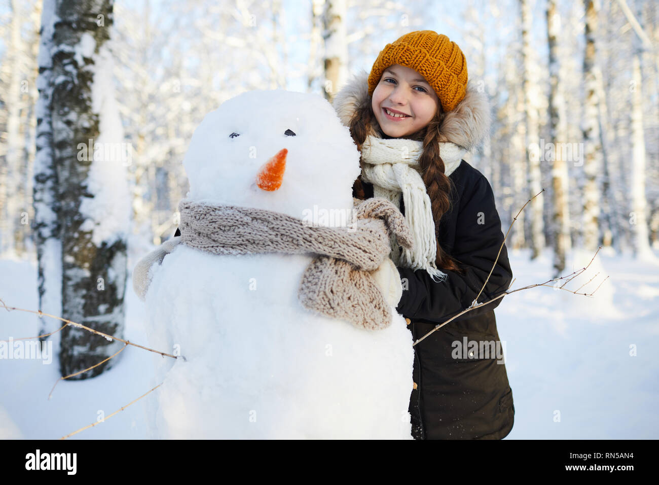 Girl posiert mit Schneemann Stockfoto