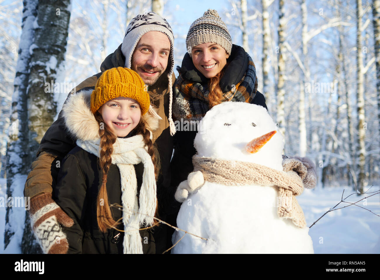 Familie posiert mit Schneemann Stockfoto