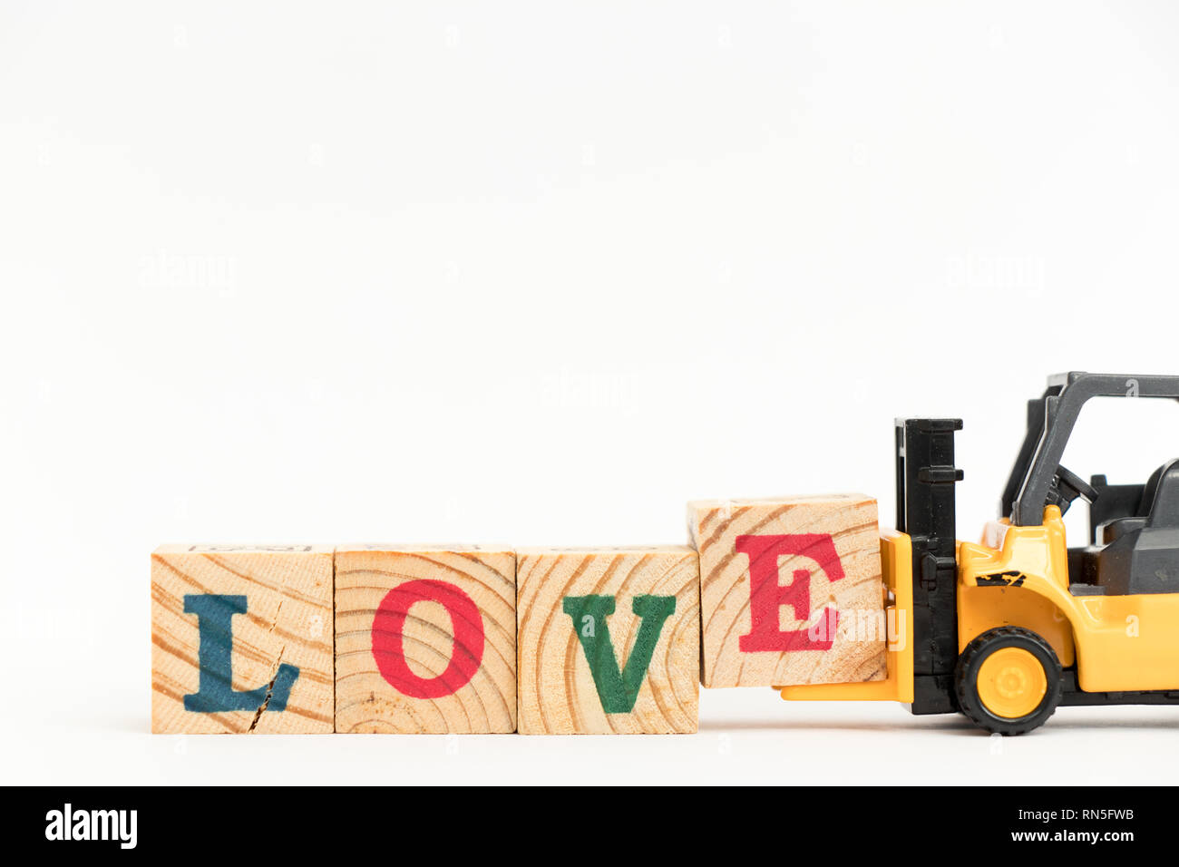 Spielzeug Gabelstapler halten Holz schreiben Block E zu Wort Liebe auf weißem Hintergrund abgeschlossen Stockfoto