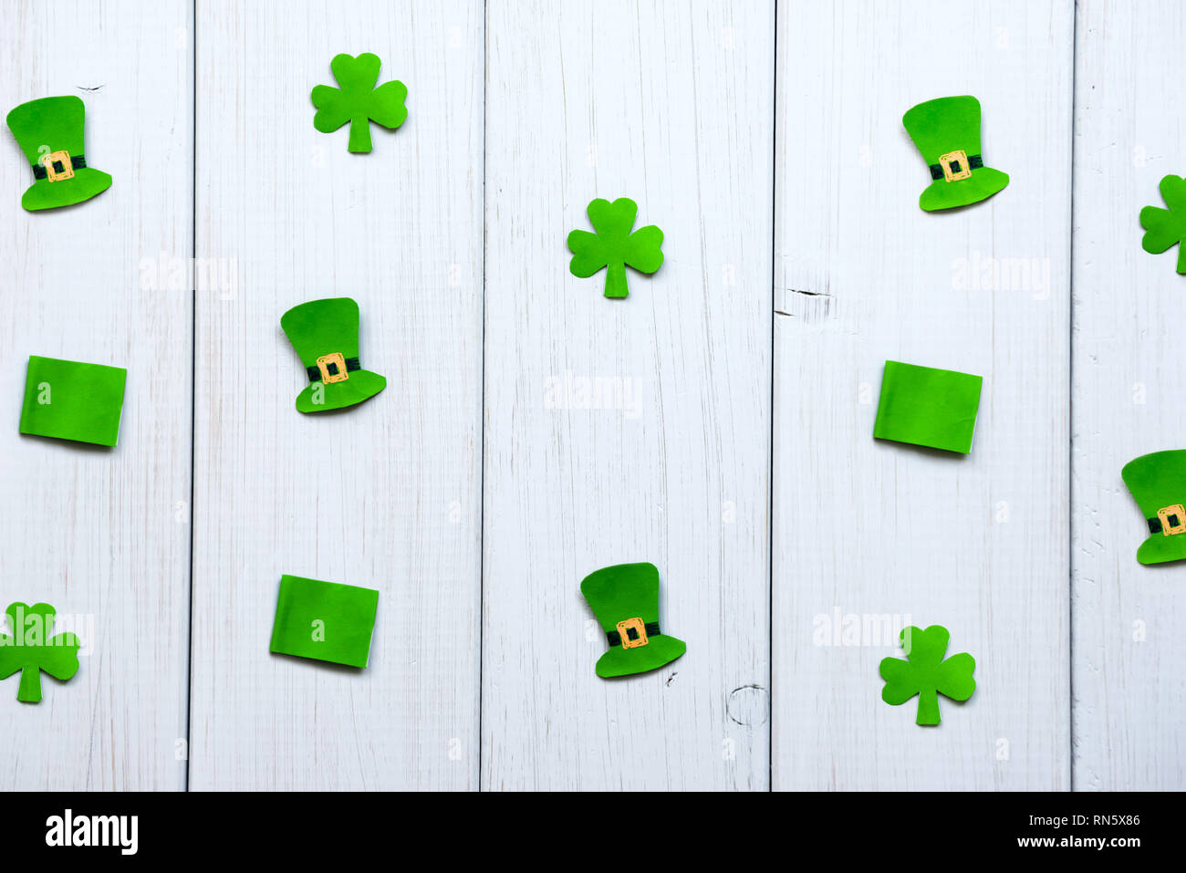 Happy St. Patrick's Day. Handwerk Papier Dekorationen in Form von leprechaun hat, Flaggen und shamrock Blätter auf einem grauen Hintergrund Holz Stockfoto