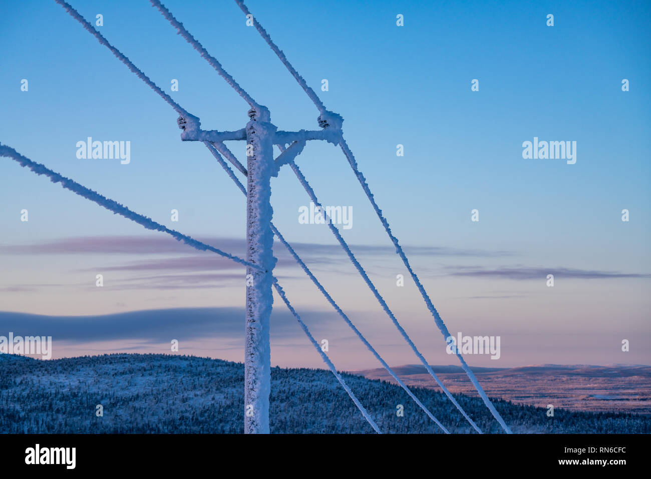 Frost und Schnee bedeckt Stromleitungen bei sehr kalten Winter in Finnland gegen Himmel Stockfoto