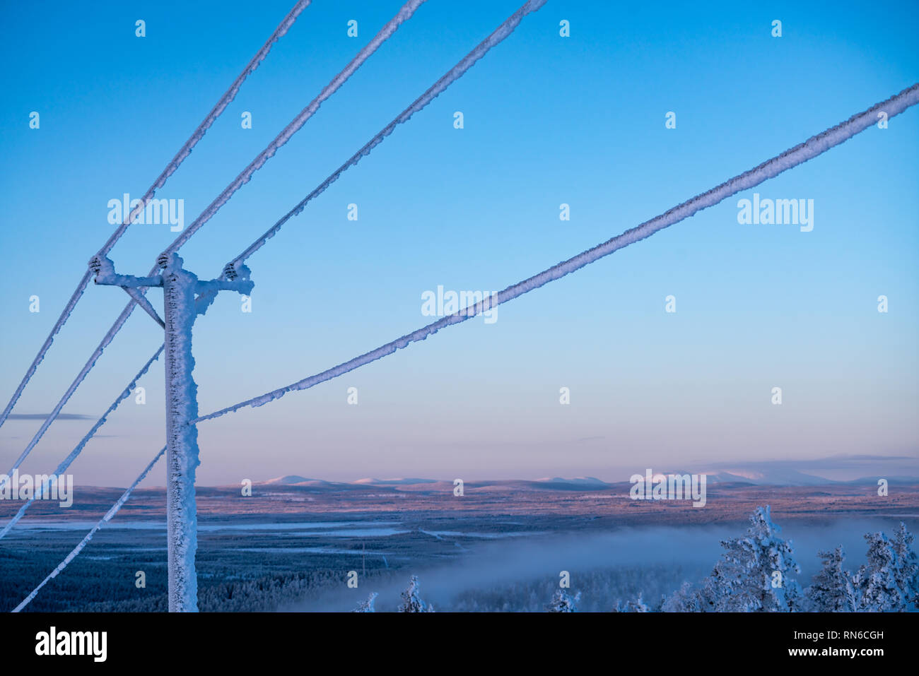 Frost und Schnee bedeckt Stromleitungen bei sehr kalten Winter in Finnland gegen Himmel Stockfoto