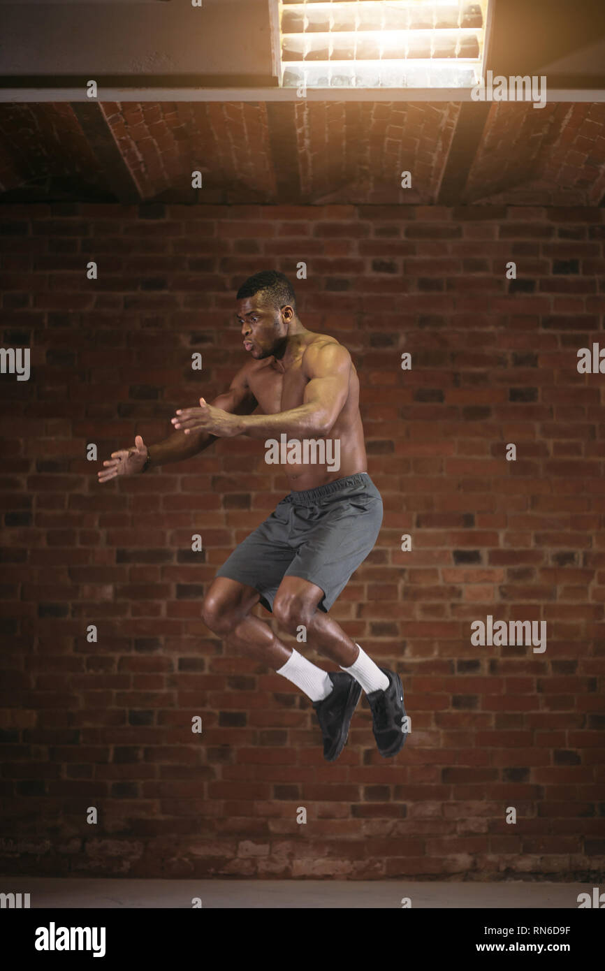 Afrikanischer Mann sprang hoch in die Luft während crossfit Workout. Lifestyle Sport macht und emotionalen Erfolg Konzept. Stockfoto