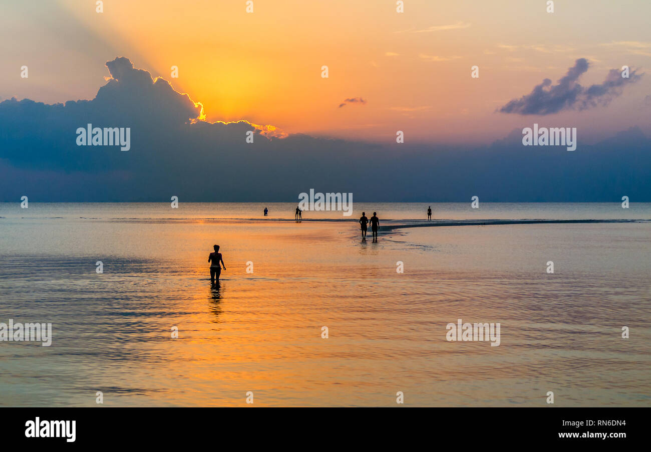 Strandurlauber auf Sandbank bei orange Sonnenuntergang über ruhige flaches Meer. Stockfoto