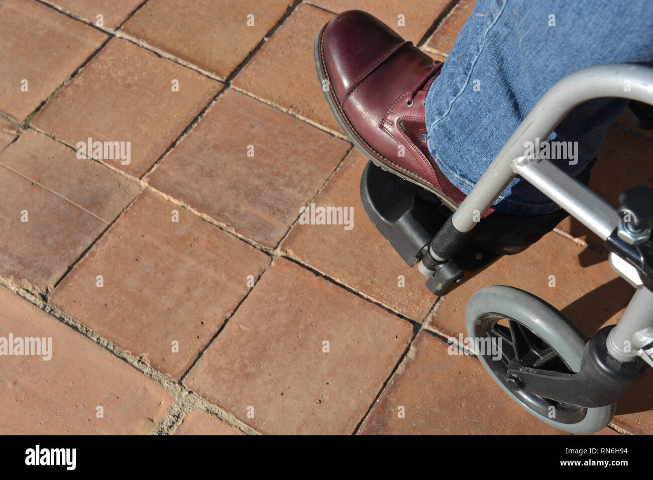 Frau in einem Rollstuhl, in Jeans und lila Stiefel, hohe Betrachtungswinkel Stockfoto