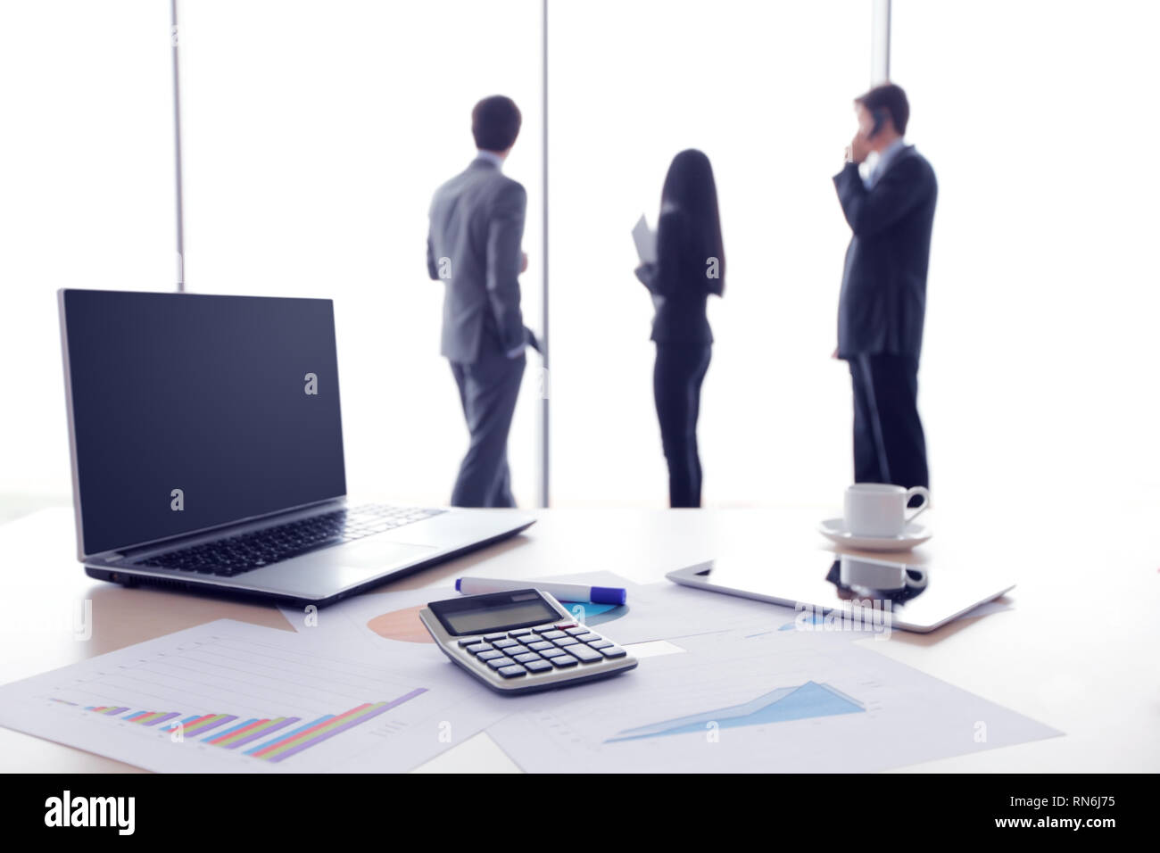Finanzielle Dokumente, Laptop, Rechner auf dem Tisch, das Business Team im Hintergrund Stockfoto