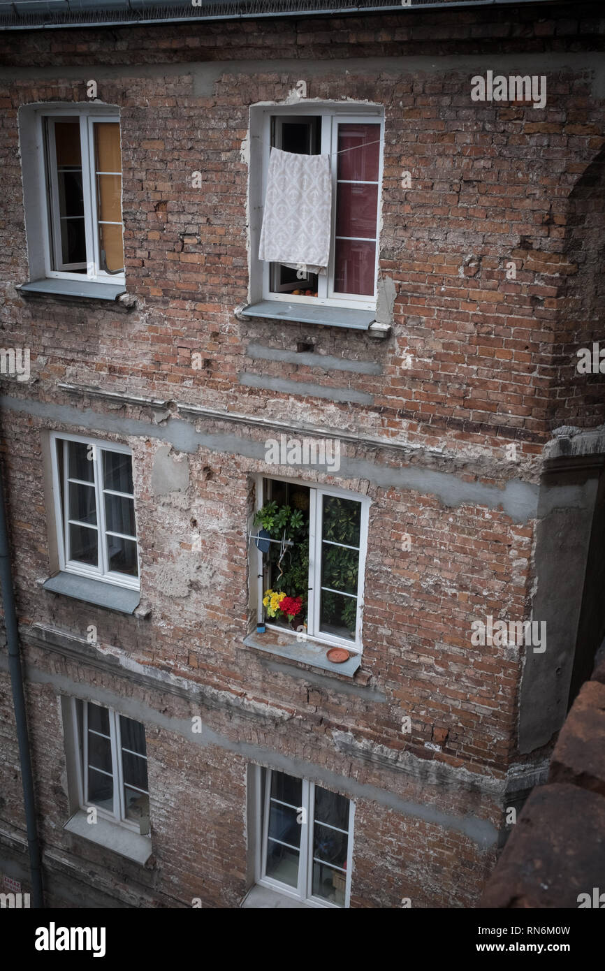 Brick Mietshaus mit Waschmaschine und Blumen, die in der Windows Stockfoto