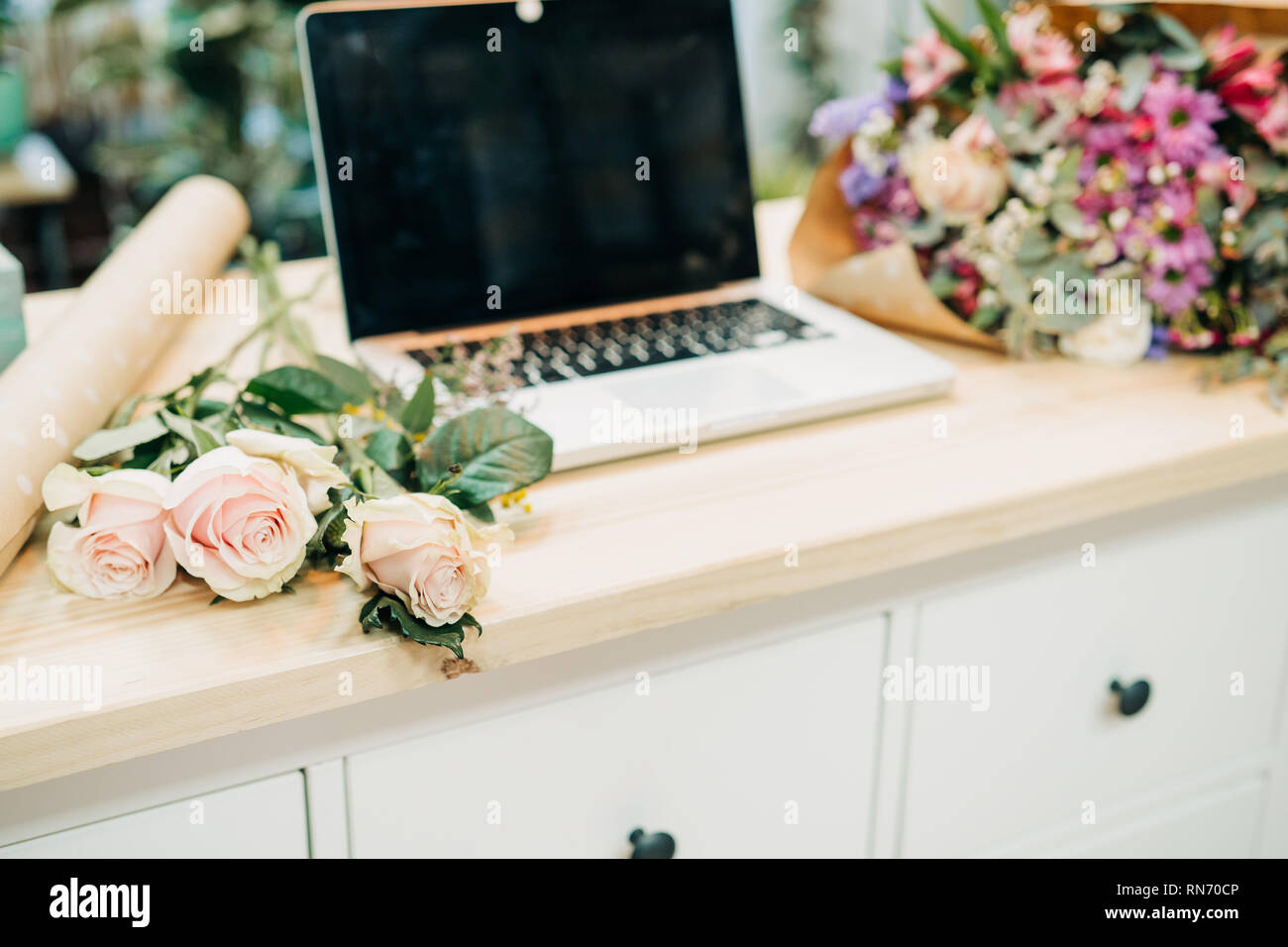 Der Florist Schreibtisch. Auf dem Tisch laptop, Rosen, Eukalyptus, Papier,  Blumen Stockfotografie - Alamy