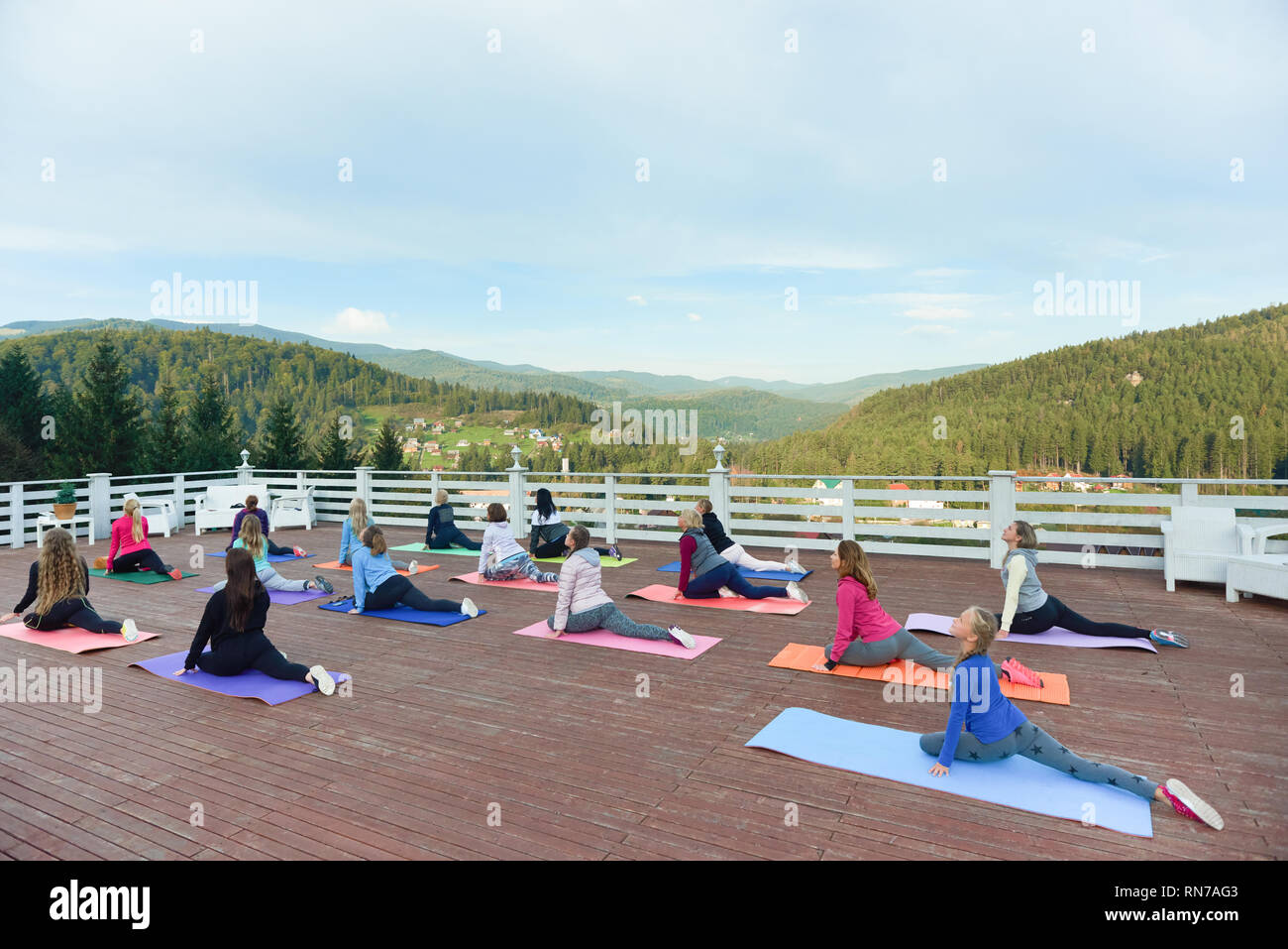 Yoga Gruppe tun, Stretching und Yoga auf Fitness Klasse mit Trainer. Flexible Frauen tragen in Sportkleidung üben am Yogamatten. Personen Ausübung auf frische Luft in den Bergen. Stockfoto
