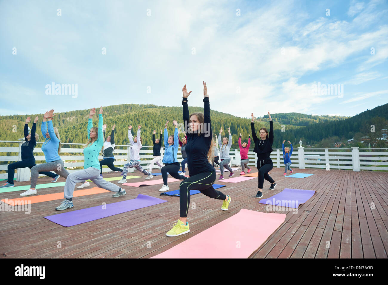 Frauen üben gering Lunge Haltung auf Yoga. Gruppe Yoga Übungen mit Trainer auf frische Luft in den Bergen. Menschen in Sportswear stretching auf speziellen Yogamatten. Stockfoto