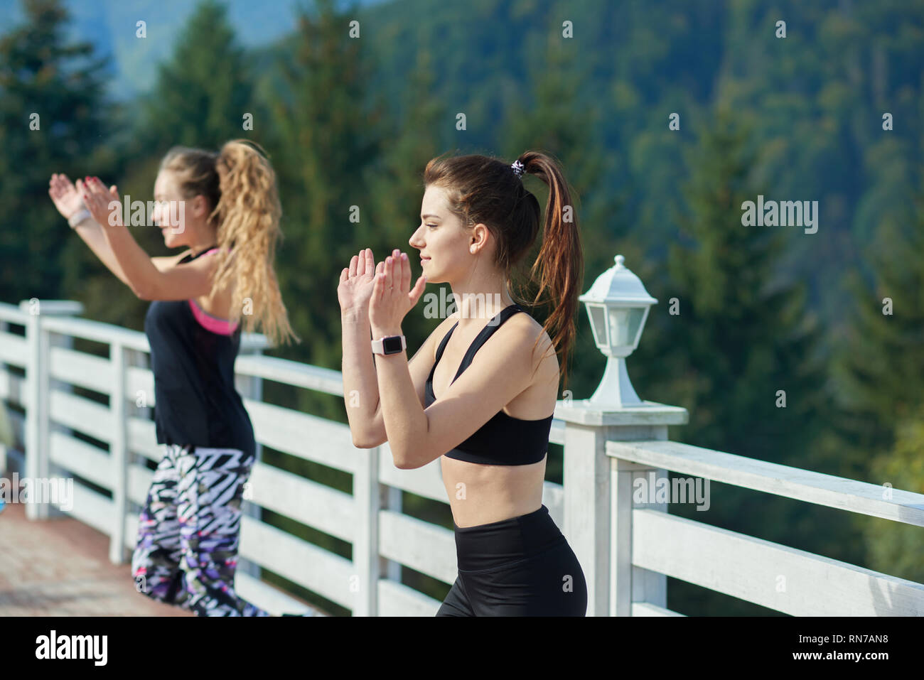 Zwei sportliche und schlanke Trainer anzeigen zu Gruppe bewegt, Händeklatschen. Energische Frauen Training und Coaching Fitness auf frische Luft rund um die Natur. Weelbeing und Sport Konzept. Stockfoto