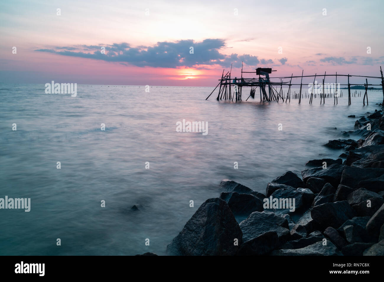 Holzsteg mit der felsigen Küste bei Sonnenuntergang. Lange Belichtung. Stockfoto