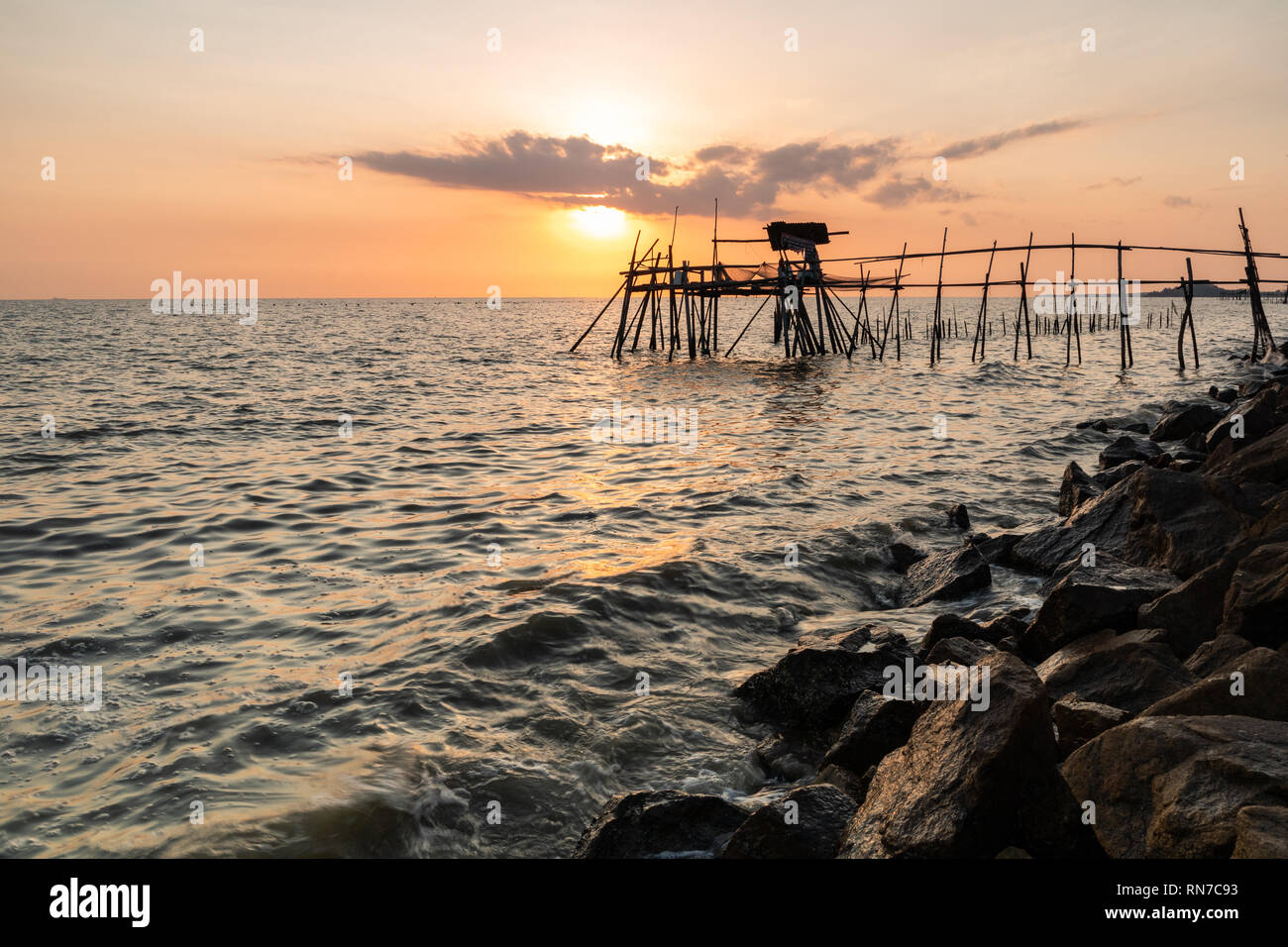 Holzsteg mit der felsigen Küste während der Goldenen Stunde Stockfoto