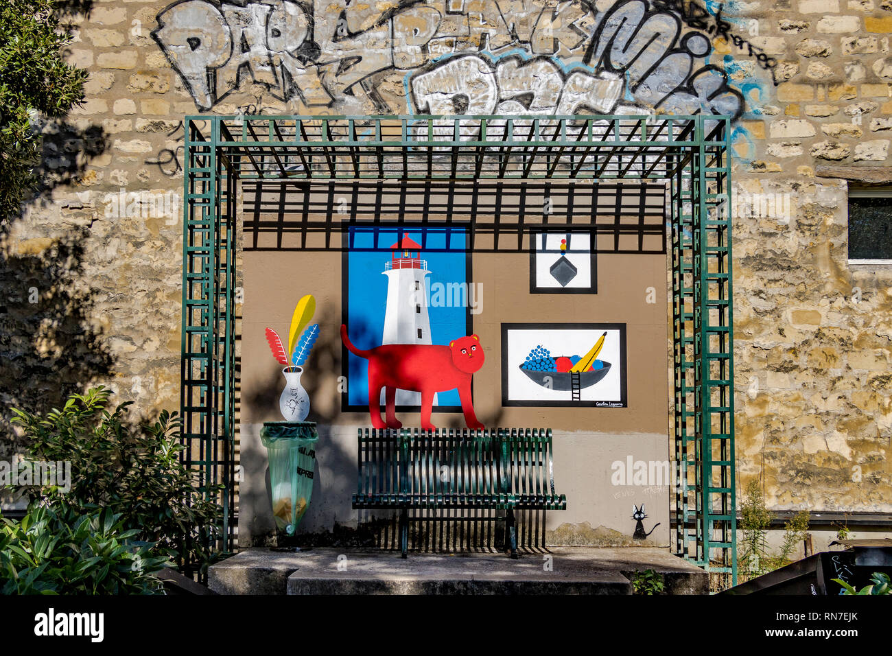 Ein grün Metall Bank mit Artwork gemalt an der Wand entlang der Promenade Plantée einer erhöhten öffentlichen Garten, Gehweg, Paris, Frankreich Stockfoto