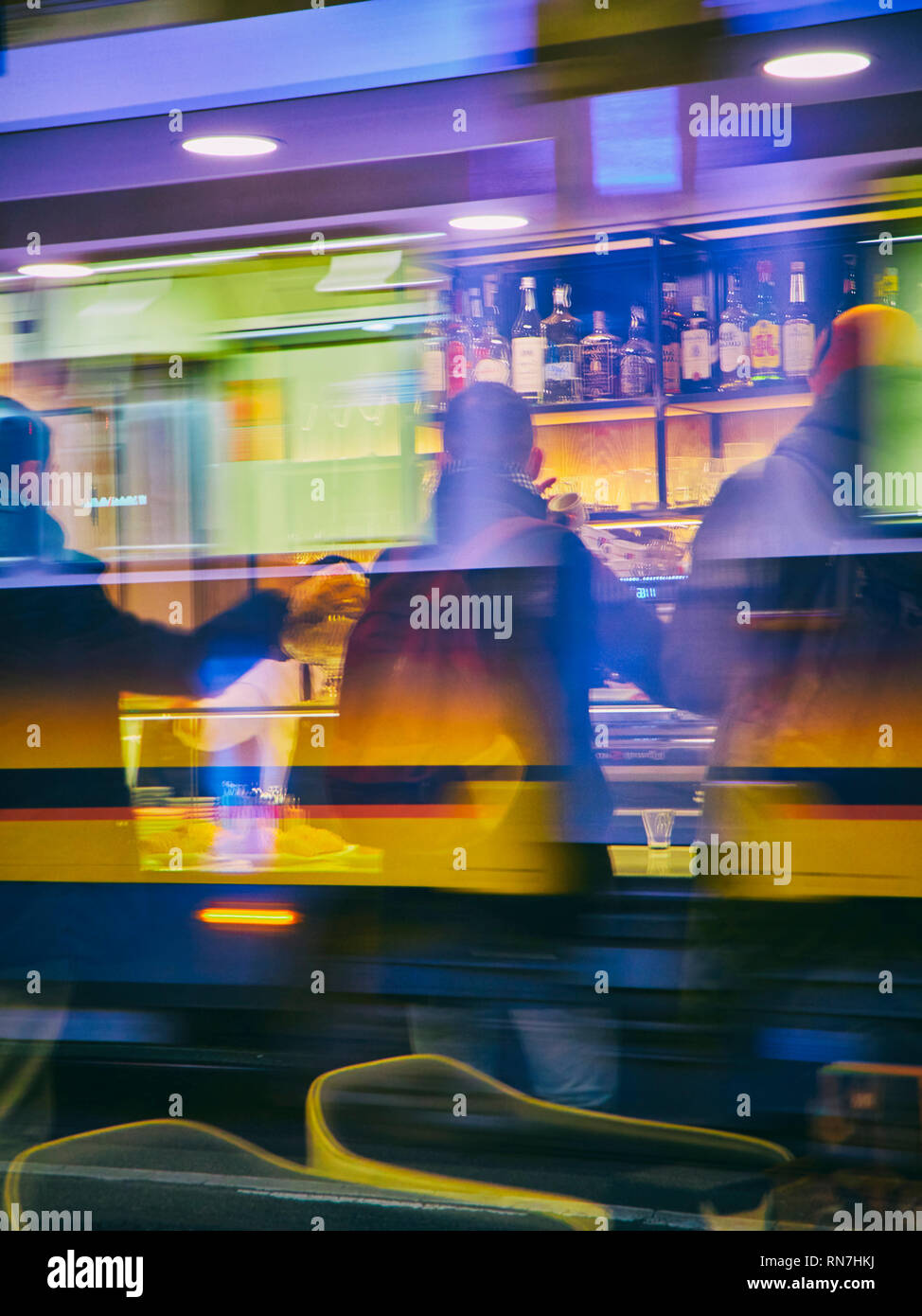 Bürger trinken einen Kaffee in einer Bar in Mailand bei Nacht. Lombardei, Italien. Blick durch die Reflexion der Fenster einer Straßenbahn. Stockfoto