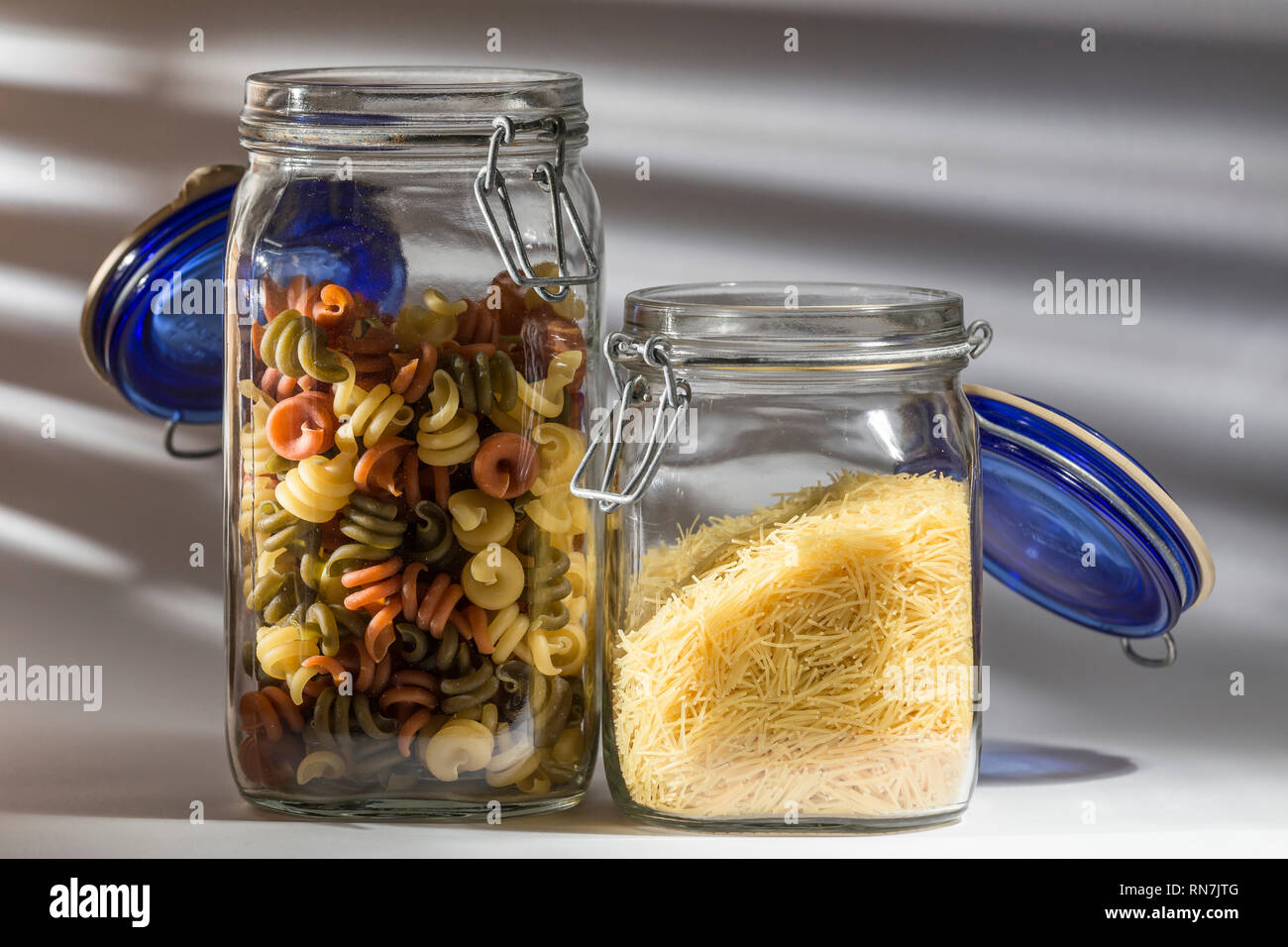Zwei Gläser, eines mit Gemüse Nudeln in Form von Spiralen und anderen Untere mit feinen Nudeln Stockfoto