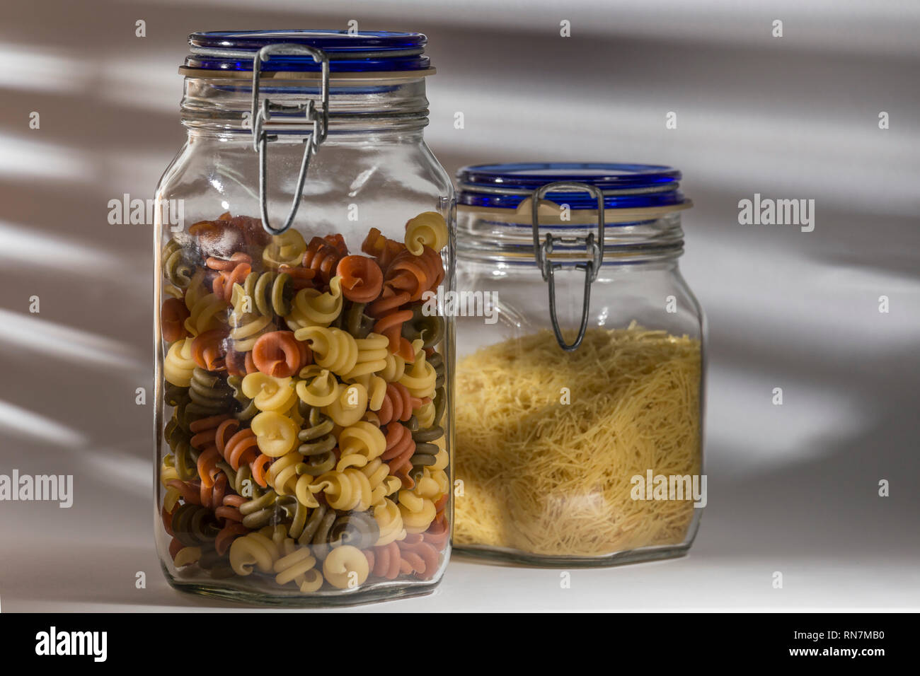 Gläser mit trockene Teigwaren, in einem Nudeln und in den anderen höher, Spiralen von Farben. Gesunde Ernährung Stockfoto