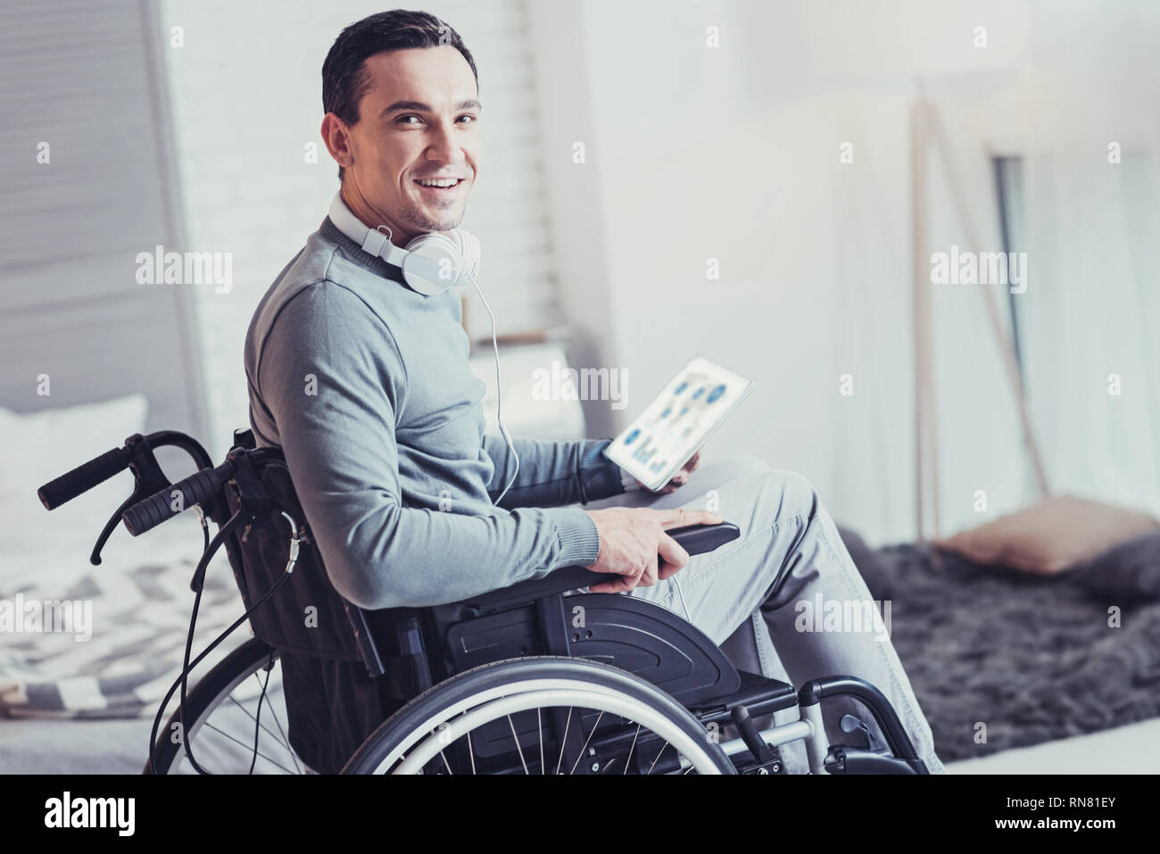 Physische Barriere. Positive behinderte Mann sitzt im Rollstuhl, während Sie auf der Suche Stockfoto