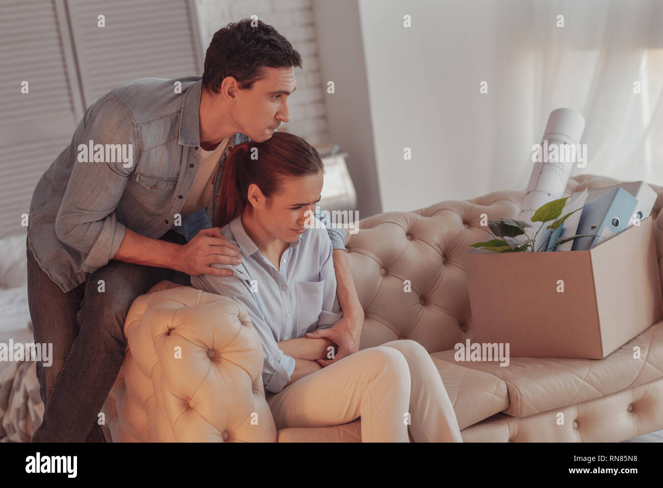 Keine Sorge. Beleidigt pissed Frau sitzt auf dem Sofa und hält die Arme über Kreuz, während Ihre sorgfältige sympathisierenden Mann ihr Sho berühren Stockfoto