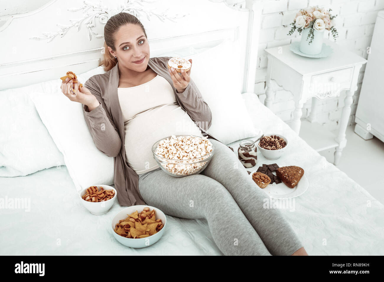 Angenehm Gute - Suche schwangere Frau in Bett im Junk Food abgedeckt Stockfoto