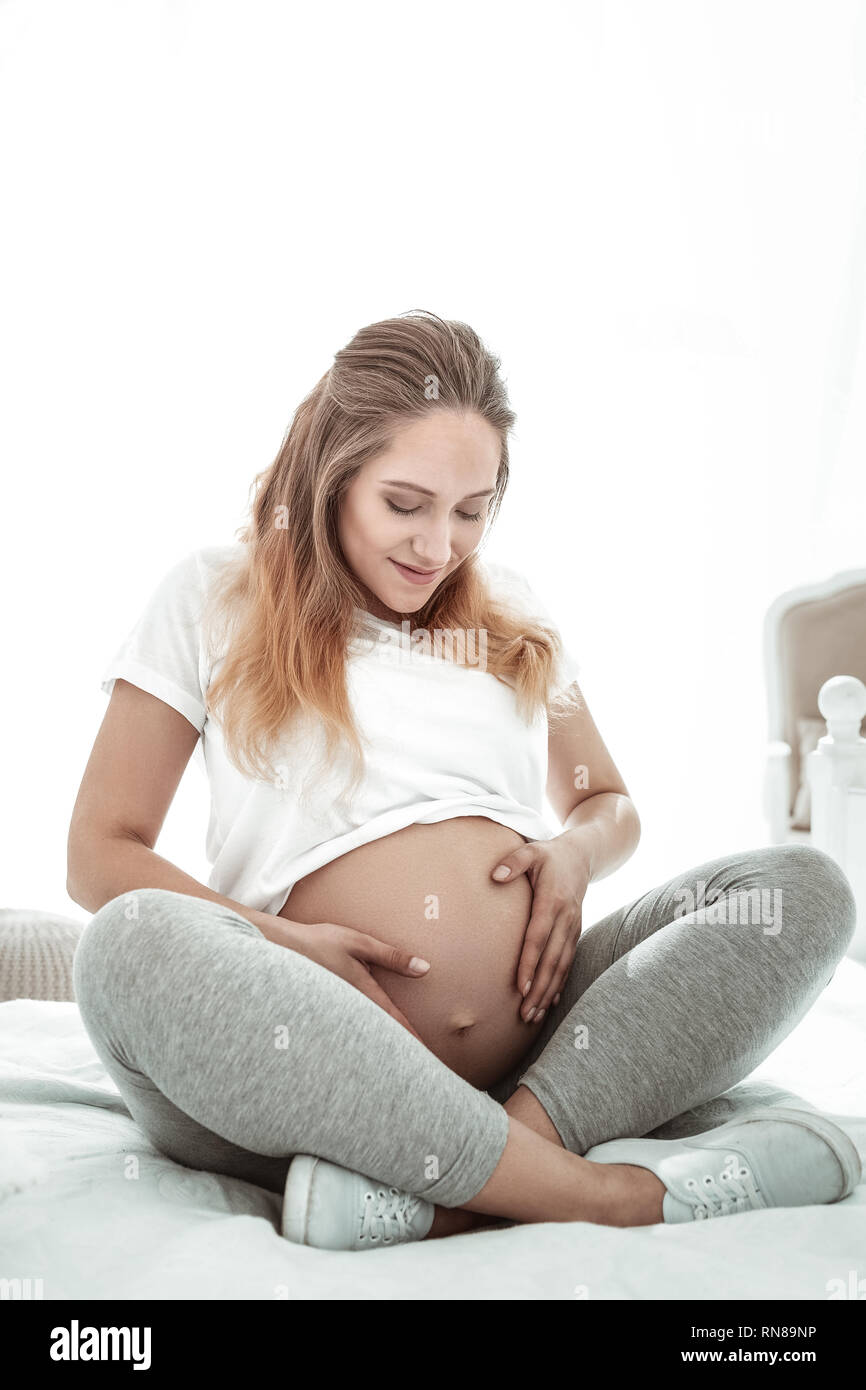 Positive angenehme Dame Sitzen mit gekreuzten Beinen und beobachten Stockfoto