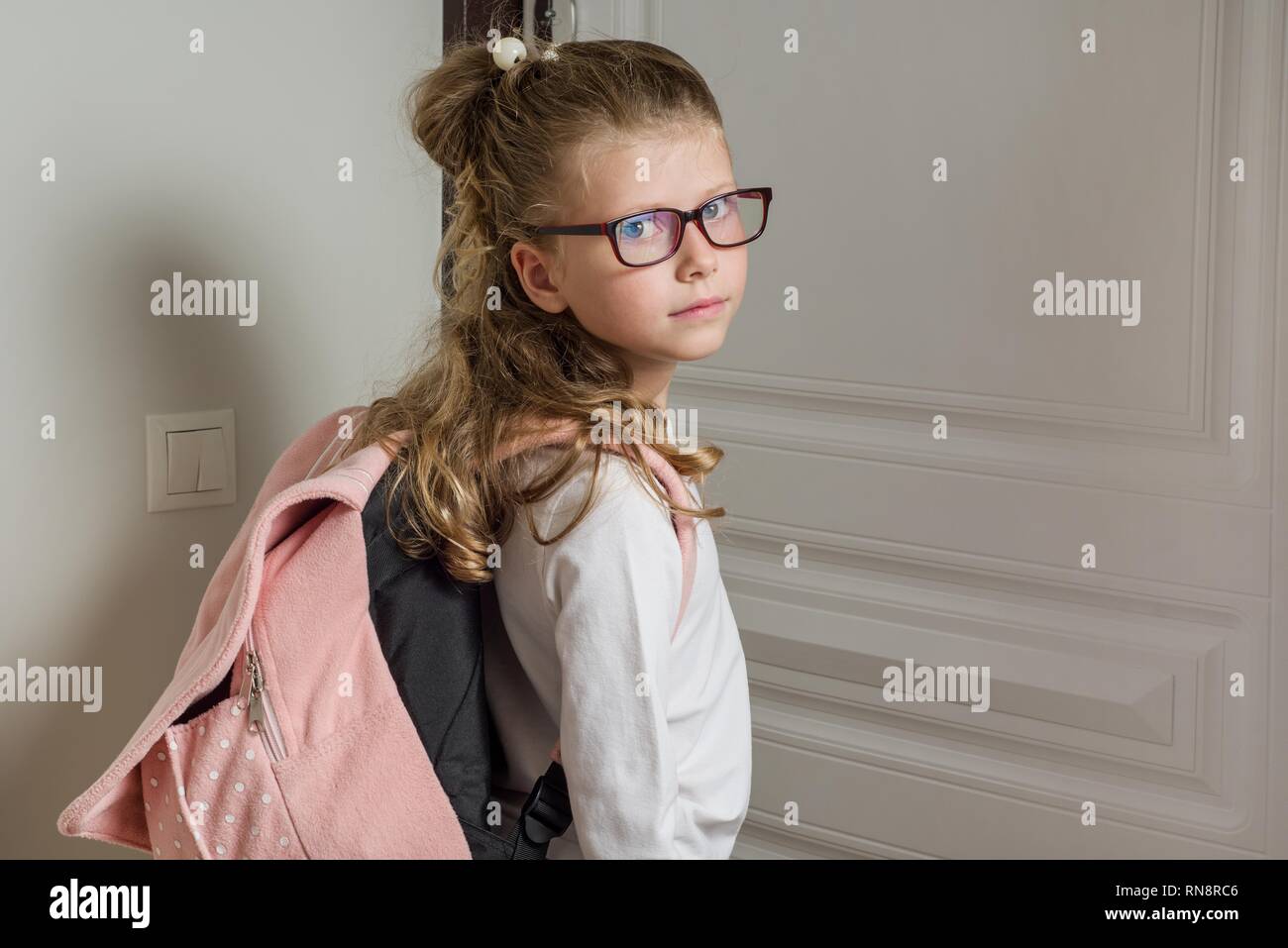 Junior Schülerin mit blonden Haaren, in die Schule zu niedlich, steht neben der Tür Stockfoto