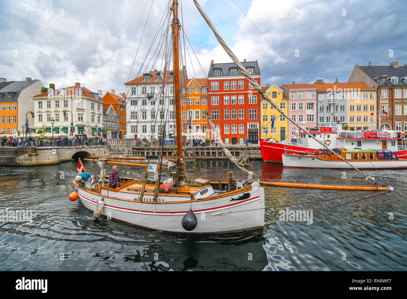 Ein älterer Mann und Frau dock Ihr Segelboot auf dem Kanal an einem bewölkten Tag im bunten 17 Nyhavn in Kopenhagen, Dänemark. Stockfoto