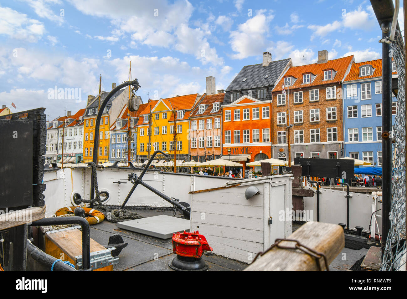 Die bunten historischen Gebäude entlang der Nyhavn Kanal steigen über das Deck eines angedockten Segelboot in Kopenhagen Dänemark Stockfoto