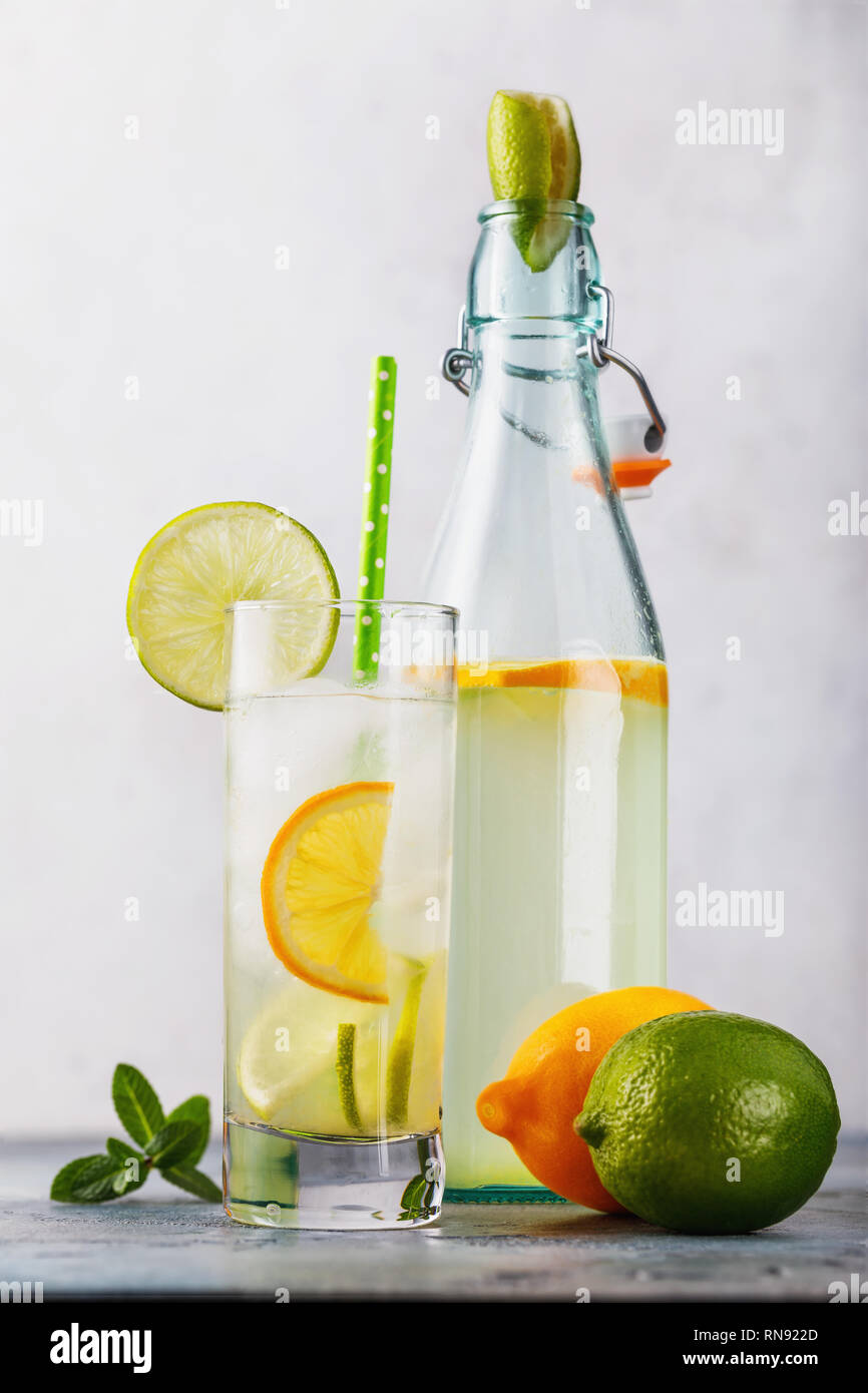 Tonic trinken mit Zitrone und Limette in ein durchsichtiges Glas mit einer offenen Flasche auf dem Tisch Stockfoto