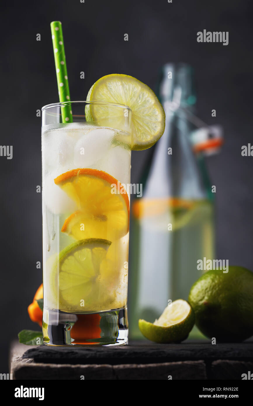 Tonic trinken mit Zitrone und Limette in ein durchsichtiges Glas mit einer offenen Flasche auf einen hölzernen Tisch Stockfoto