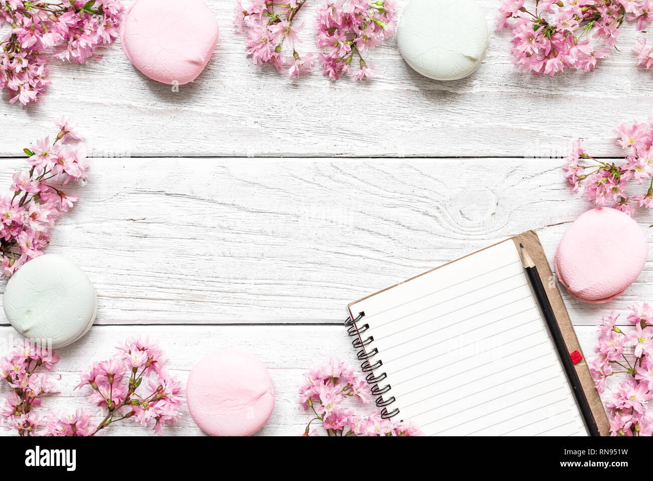 Mockup leeres Papier Notebook im Rahmen aus rosa blühenden Frühling Zweigniederlassungen von Kirsche und Makronen mit Kopie Raum. top anzeigen. Flach Stockfoto