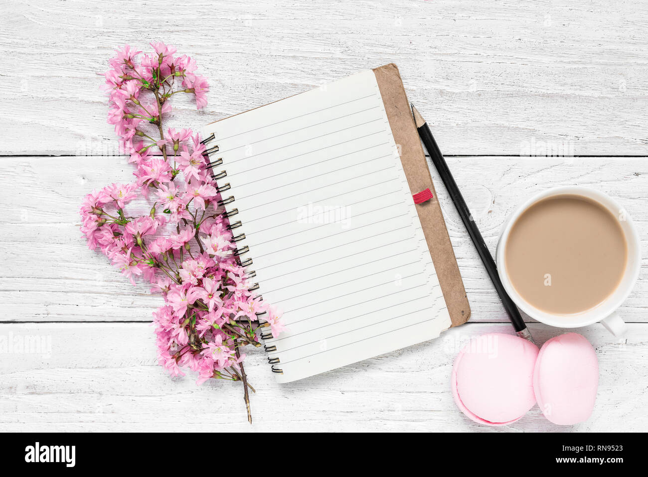 Kreative Gestaltung mit Feder cherry blühenden Blumen, leere Notepad, Makronen und Kaffee Tasse auf weißem Holz- Hintergrund. Flach. top Aussicht. Wir Stockfoto