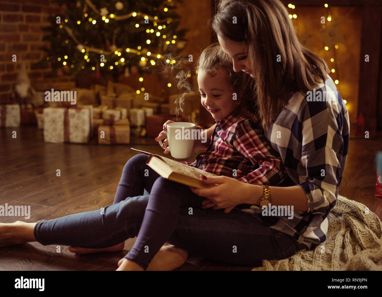 Hübsche Mutter Lesung ein Buch für ihre Tochter in einer ruhigen, Winter eveneing Stockfoto