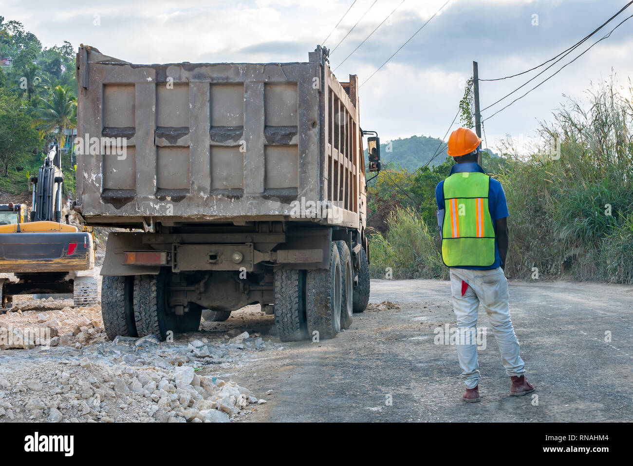 Männliche Bauarbeiter in Helm und Warnweste stehen im Straßen Verkehr beim Lkw zu stoppen auf der Straße Baustelle neu positionieren Stockfoto