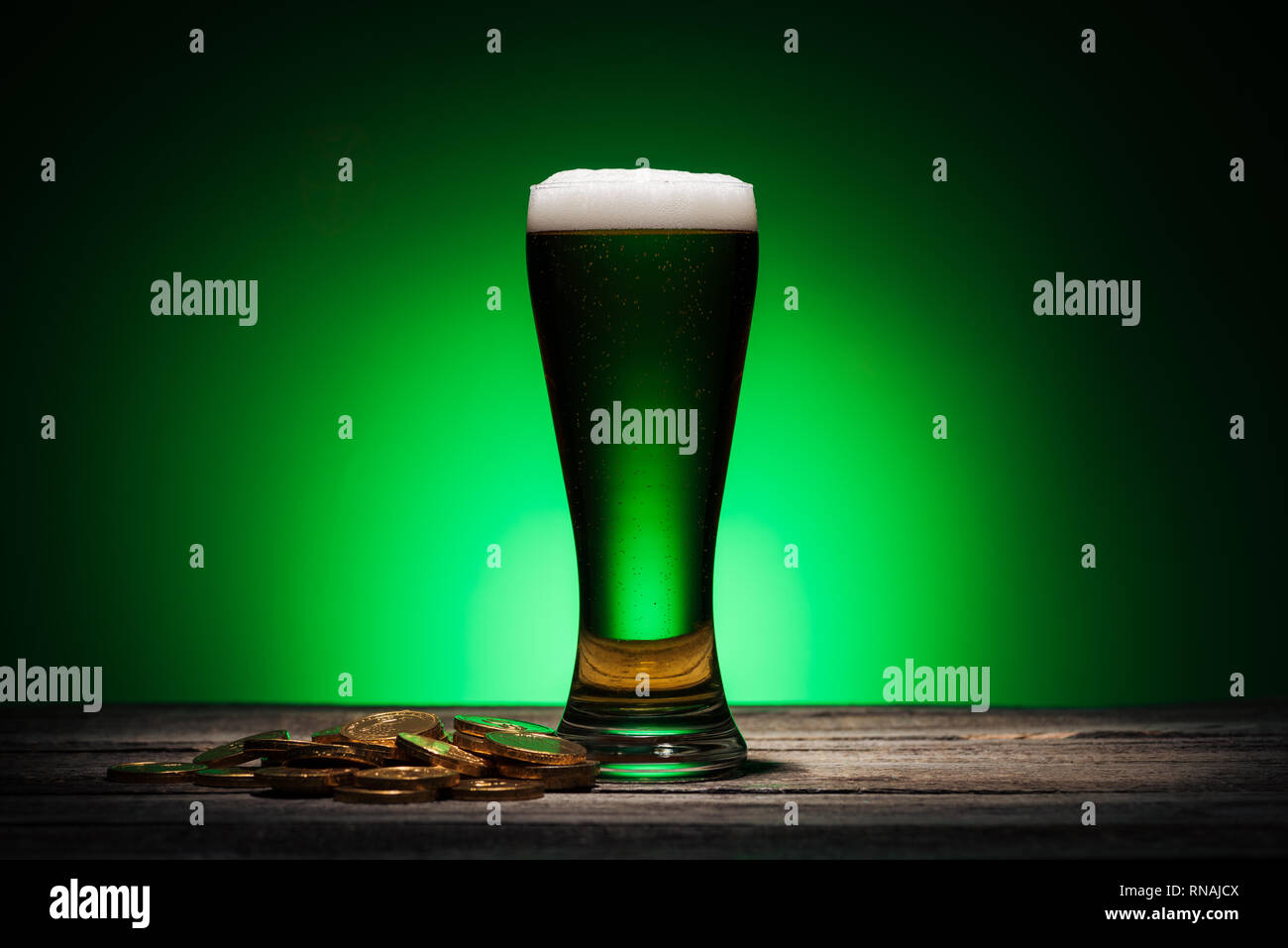 Glas grün Bier in der Nähe von Golden Coins auf st patricks day auf grünem Hintergrund Stockfoto