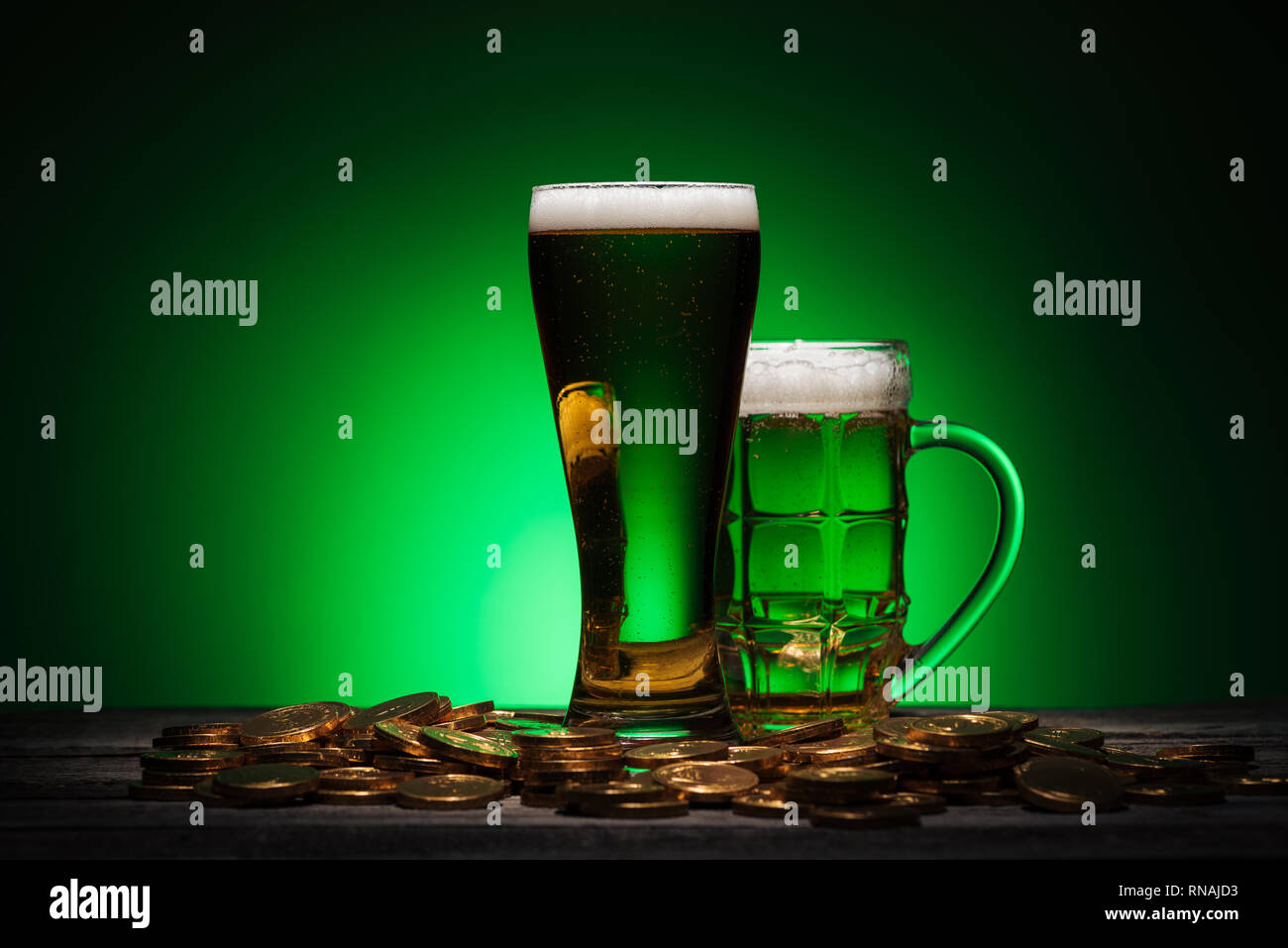 Gläser Bier stehen auf hölzernen Tisch auf st patricks day auf grünem Hintergrund Stockfoto