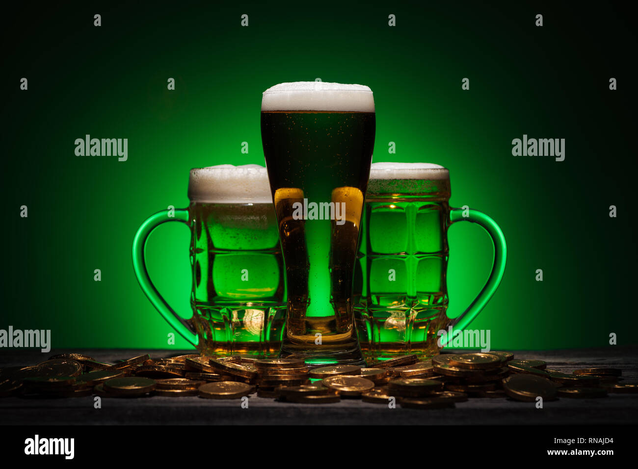 Gläser Bier stehend in der Nähe von Golden Coins auf st patricks day auf grünem Hintergrund Stockfoto